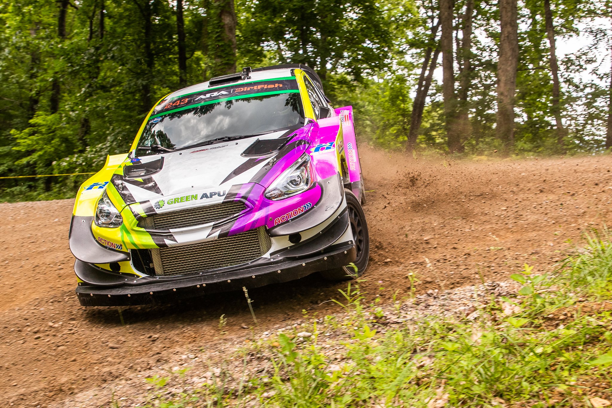 Green APU Rally Racing Car drifting through dirt corner